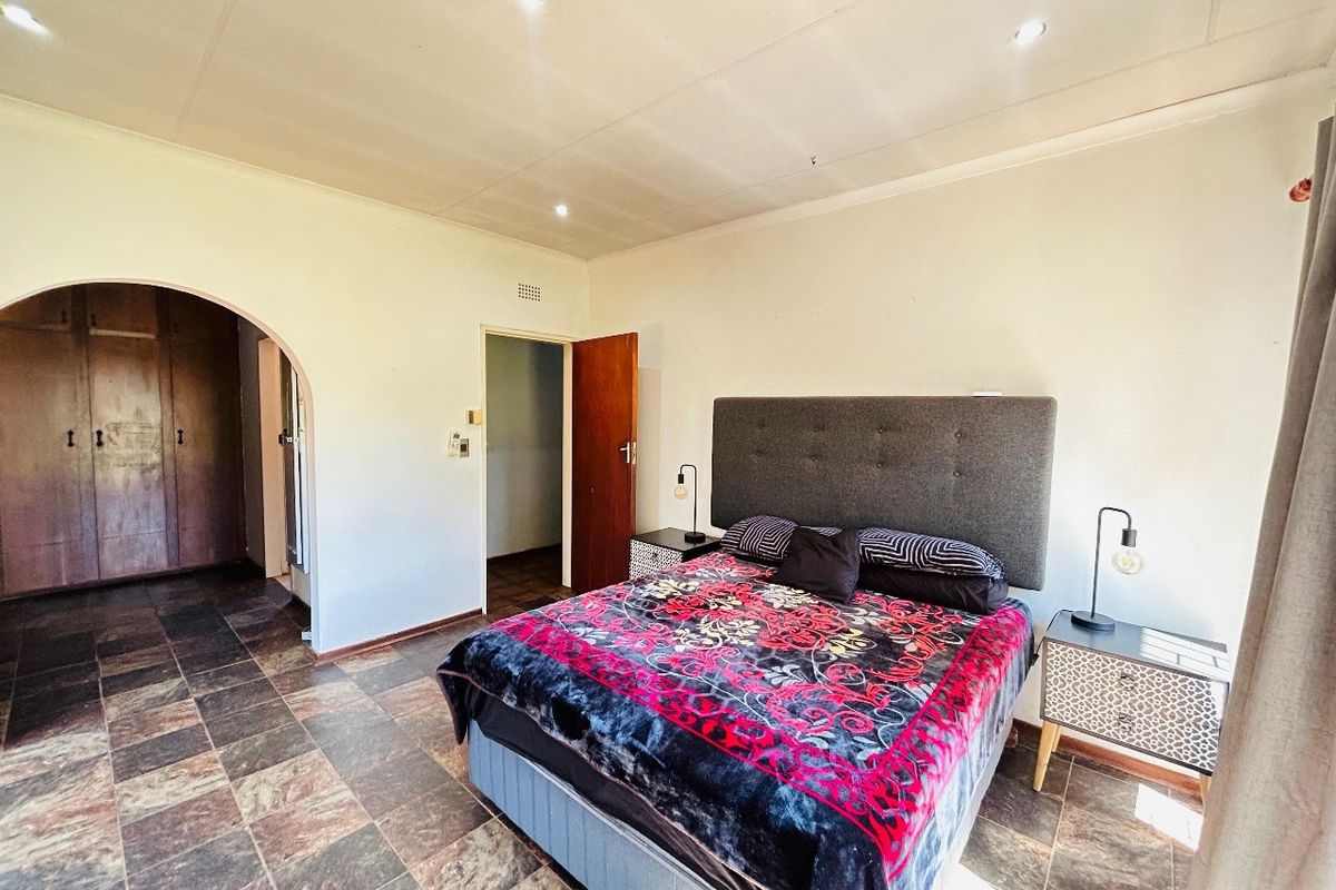 Spacious bedroom featuring tiled flooring, recessed downlighting, and a classic arched entryway leading to built-in storage.