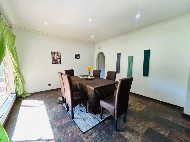 A dining room featuring tiled flooring, recessed downlighting, and an arched entryway leading to adjacent living spaces.