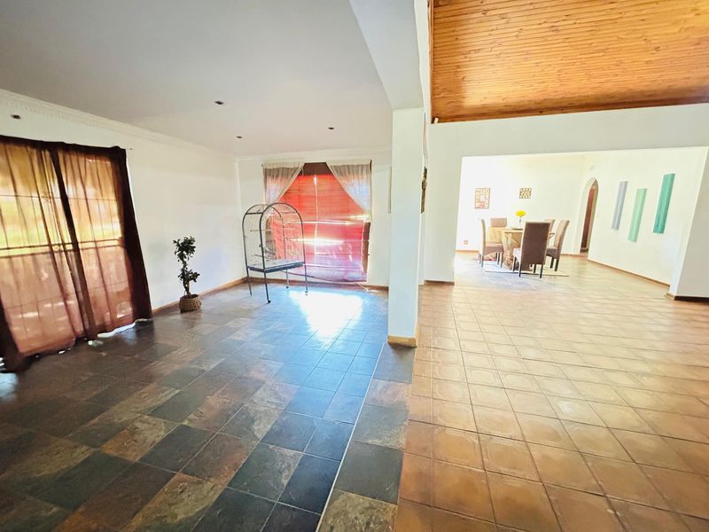 Spacious open-plan living and dining area featuring tiled flooring, a timber-clad ceiling, and recessed lighting, offering a versatile layout for family living.