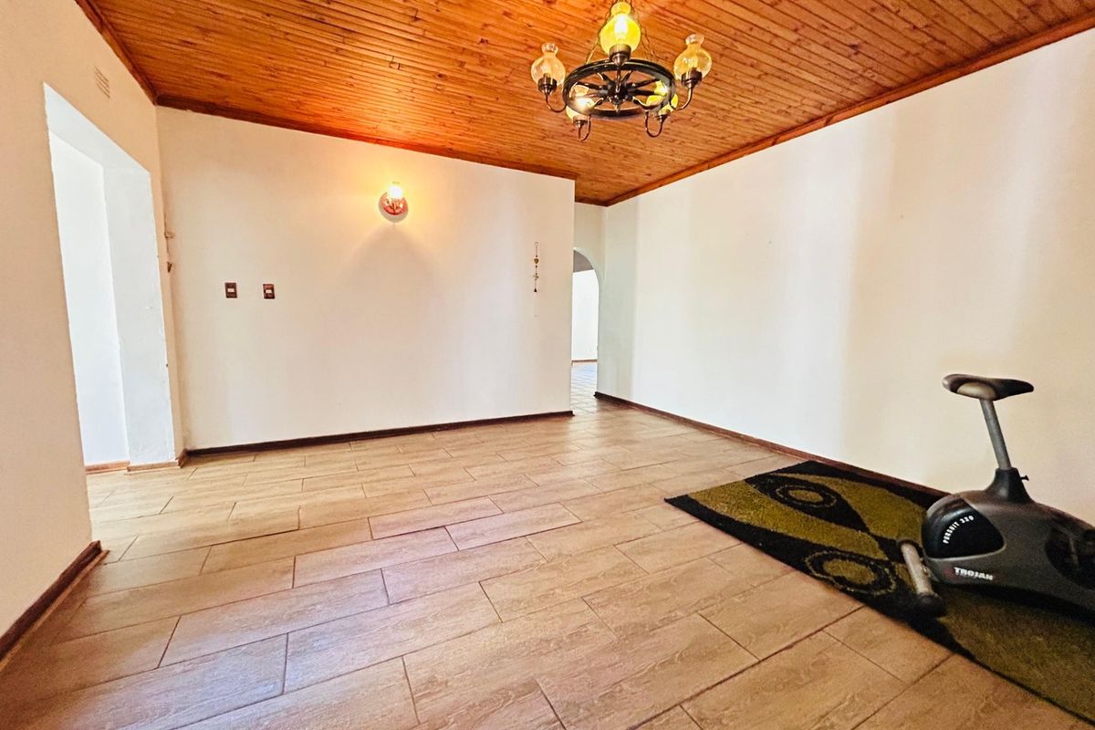 A spacious living area featuring a warm timber-paneled ceiling and neutral tiled flooring, offering a versatile blank canvas for interior design.