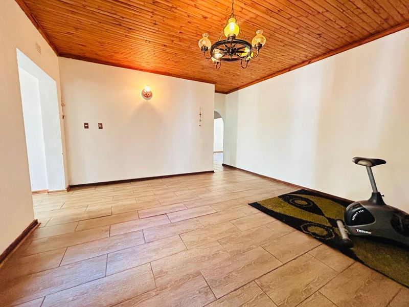 A spacious living area featuring a warm timber-paneled ceiling and neutral tiled flooring, offering a versatile blank canvas for interior design.