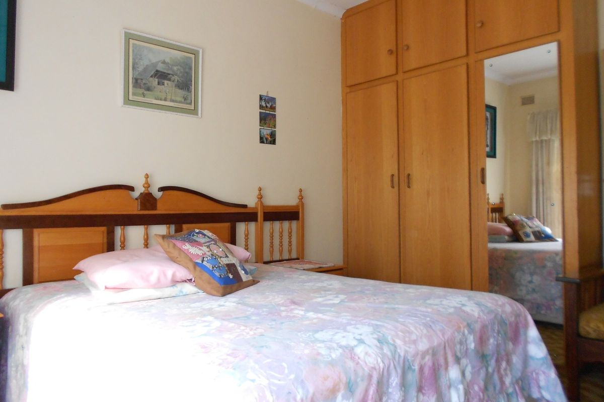 A bedroom featuring a built-in wooden wardrobe with a mirrored door, providing ample storage space.