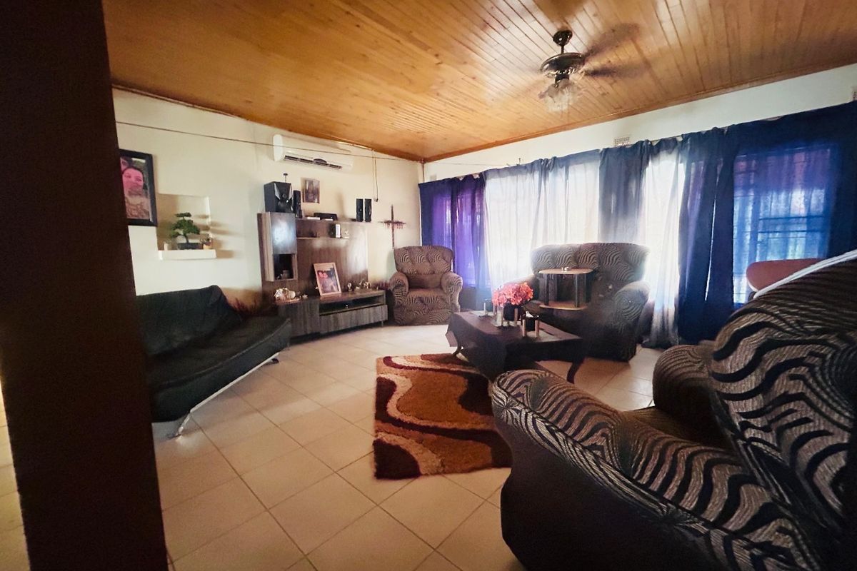 A living room featuring a timber tongue and groove ceiling, tiled flooring, and a wall-mounted split system air conditioner.