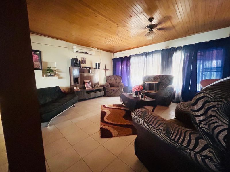A living room featuring a timber tongue and groove ceiling, tiled flooring, and a wall-mounted split system air conditioner.