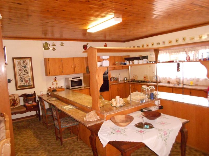 A dated kitchen featuring wooden ceiling panels, built-in cabinetry, and a breakfast bar, offering potential for a modern renovation.