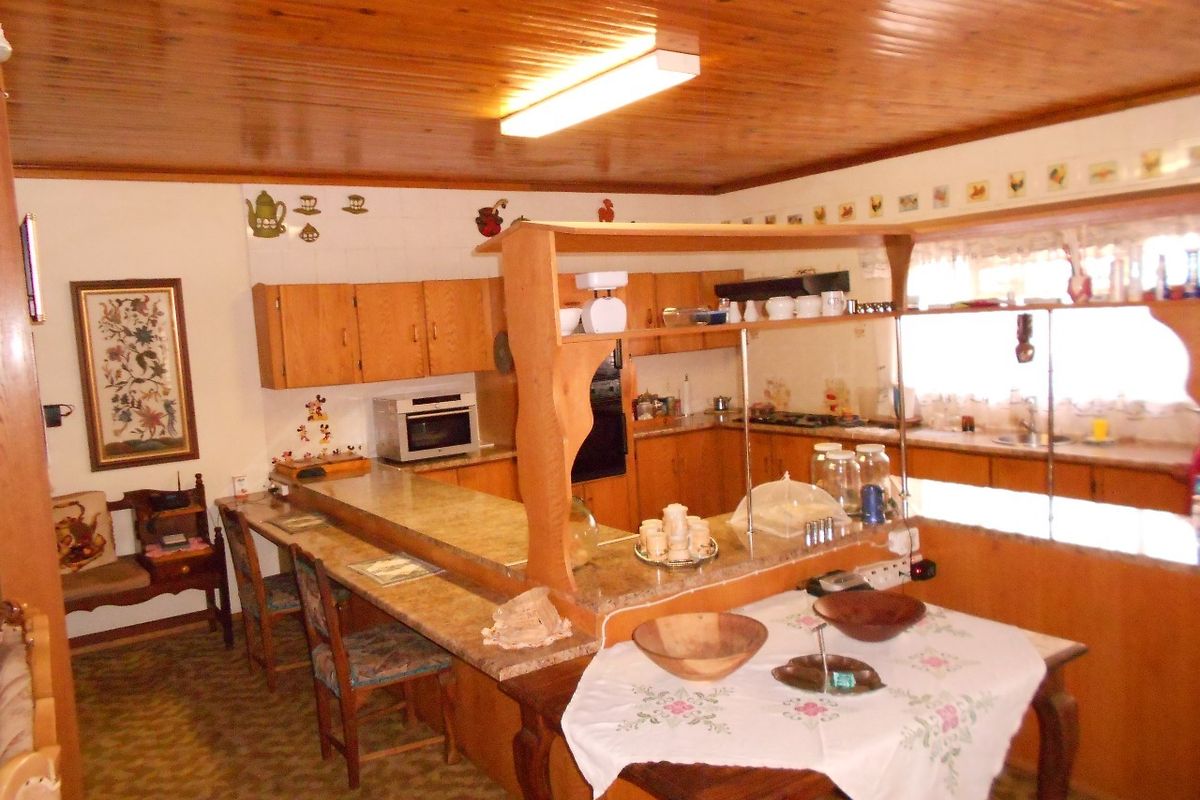 A dated kitchen featuring wooden ceiling panels, built-in cabinetry, and a breakfast bar, offering potential for a modern renovation.