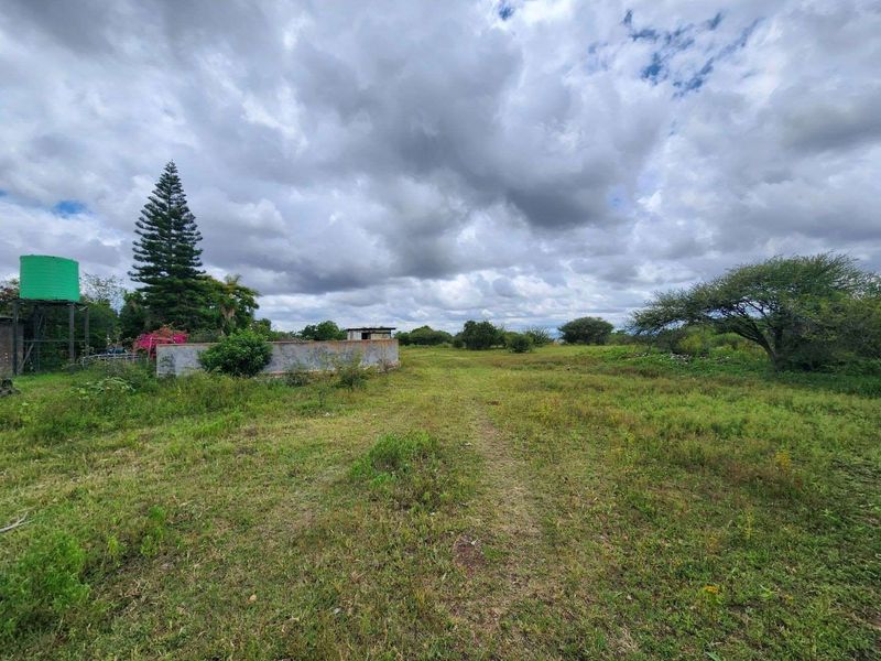 Expansive open land area featuring a water storage tank and a masonry boundary wall, suitable for agricultural or development use.
