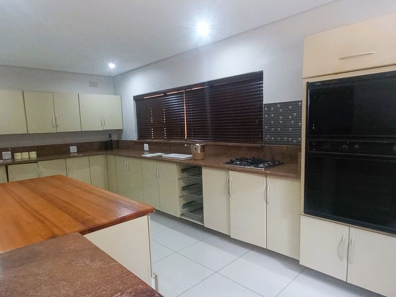 Spacious kitchen featuring extensive built-in cabinetry, laminate countertops, a built-in double oven, gas hob, and tiled flooring with recessed lighting.