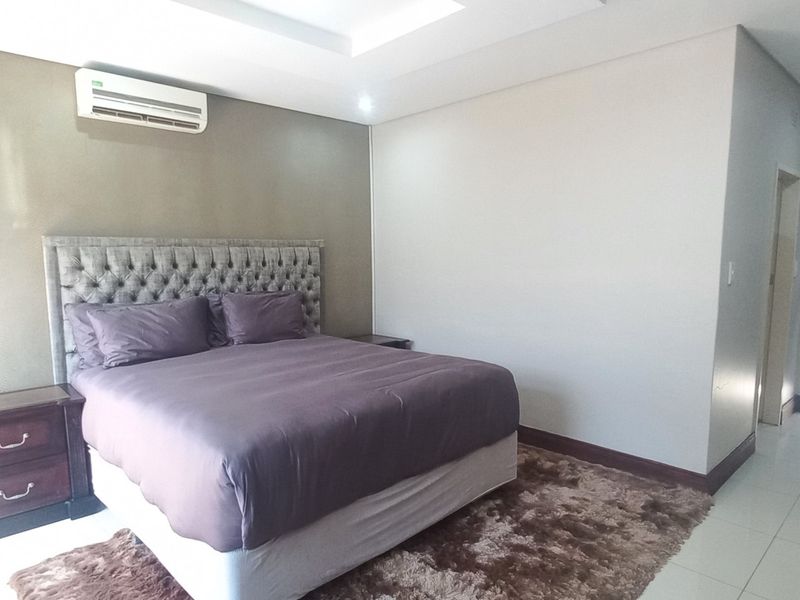 Spacious bedroom featuring tiled flooring, recessed ceiling lighting, and a wall-mounted split-system air conditioner.