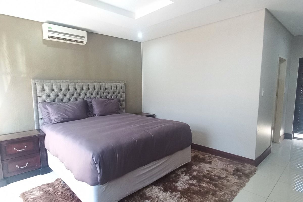 Spacious bedroom featuring tiled flooring, recessed ceiling lighting, and a wall-mounted split-system air conditioner.