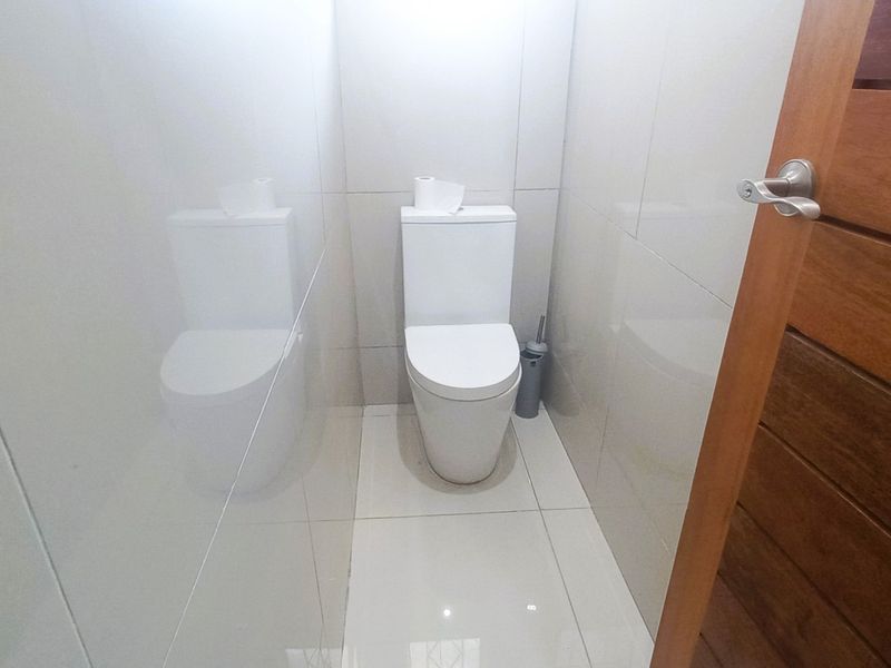 A clean and modern guest bathroom featuring neutral wall and floor tiles and a contemporary toilet suite.