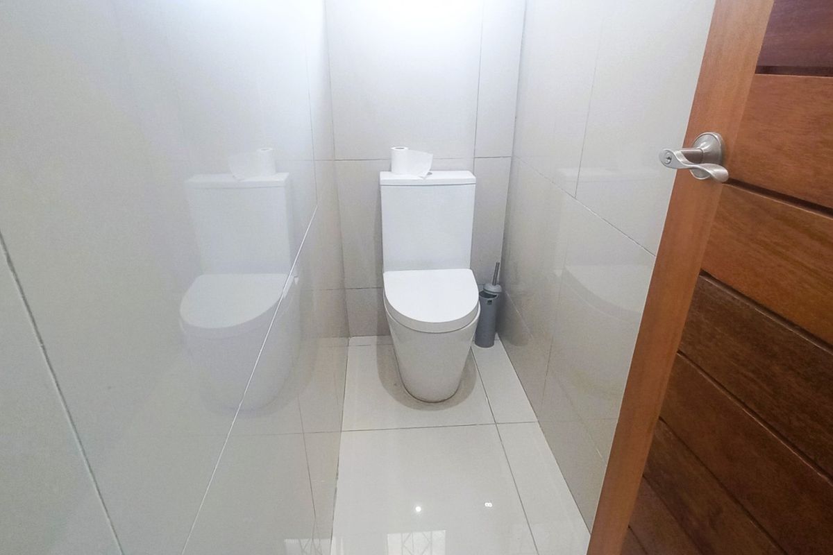 A clean and modern guest bathroom featuring neutral wall and floor tiles and a contemporary toilet suite.