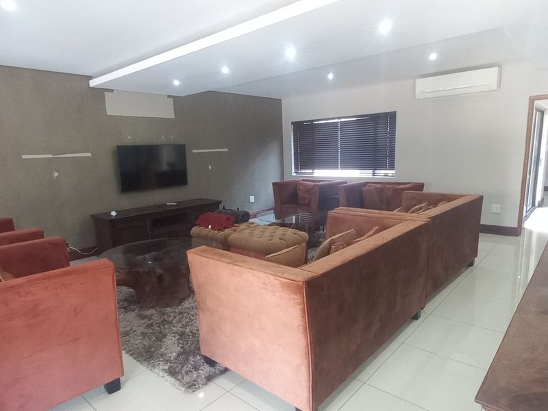 Spacious living room featuring tiled flooring, recessed ceiling lighting, and a wall-mounted air conditioning unit.
