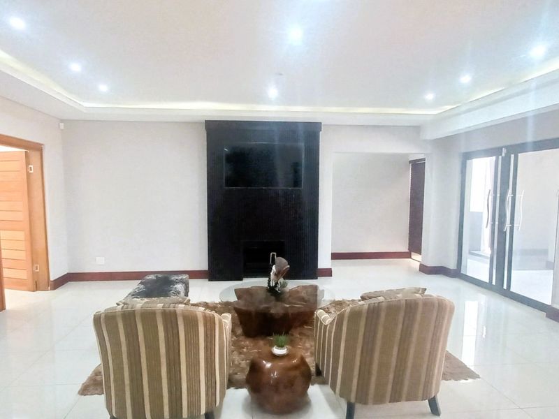 Spacious living room featuring tiled flooring, recessed ceiling lighting, and a prominent built-in fireplace, with direct access to an outdoor area via sliding glass doors.
