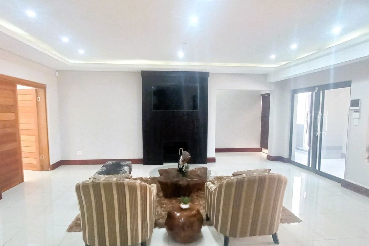 Spacious living room featuring tiled flooring, recessed ceiling lighting, and a prominent built-in fireplace, with direct access to an outdoor area via sliding glass doors.