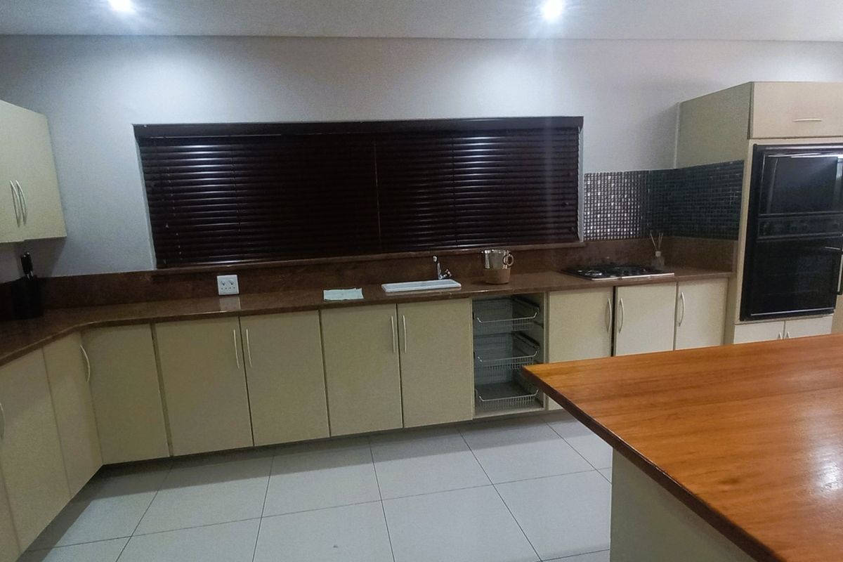 Spacious kitchen featuring extensive built-in cabinetry, stone countertops, a central island, and integrated appliances including a double wall oven and gas cooktop.
