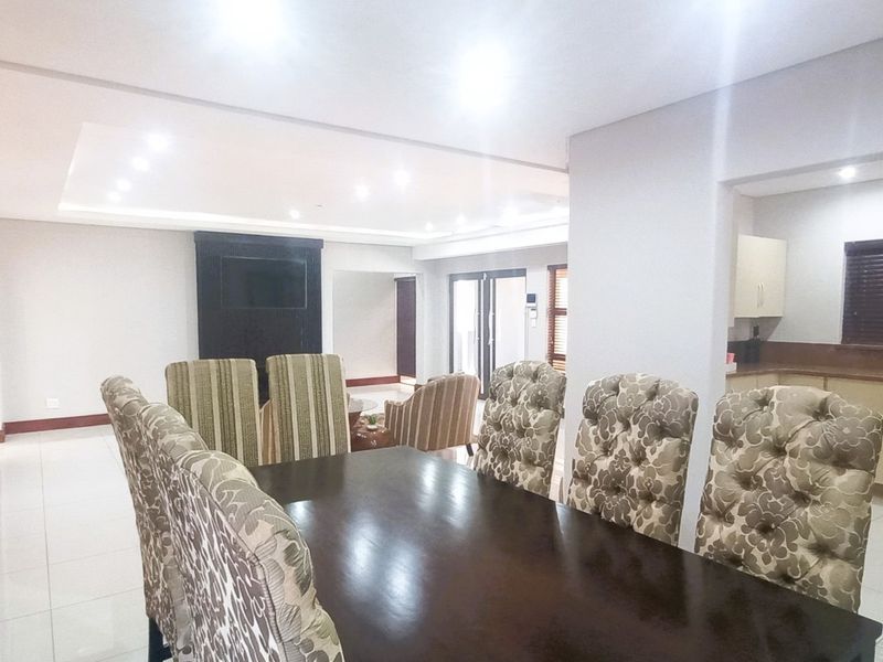 Spacious open-plan living and dining area featuring tiled floors, recessed lighting, and a functional kitchen with built-in cabinetry and a breakfast bar.