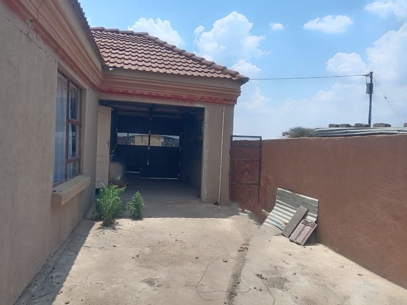 Exterior view of a residential garage with a concrete driveway and perimeter wall, showing signs of wear and maintenance requirements.