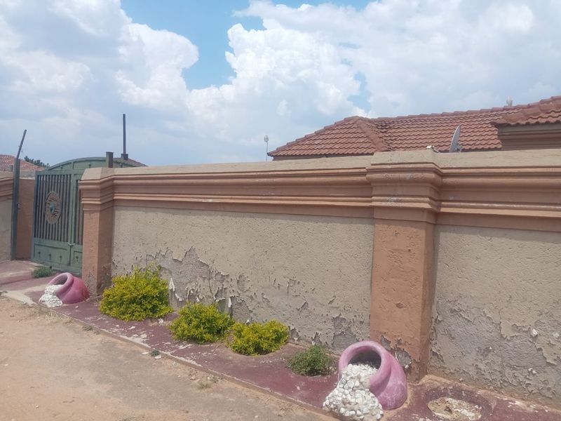 Front exterior view of the property featuring a boundary wall with a metal gate and tiled roof structure.