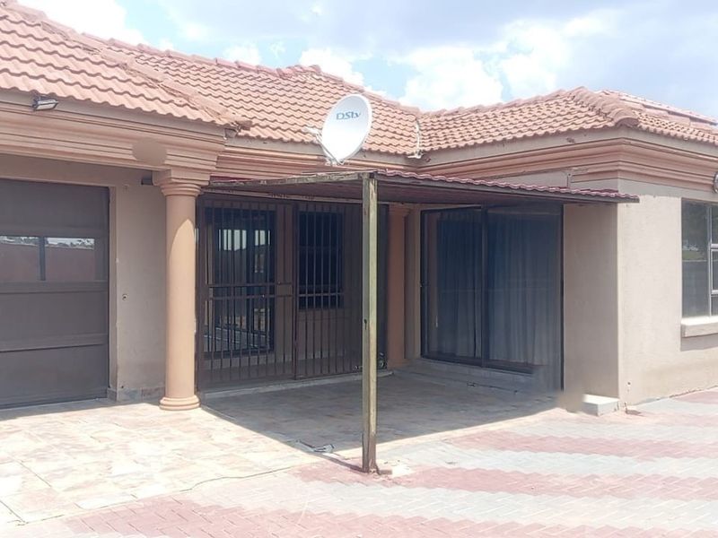 Front elevation of a single-story house featuring a paved driveway, integrated garage, and a covered patio area with security gates.