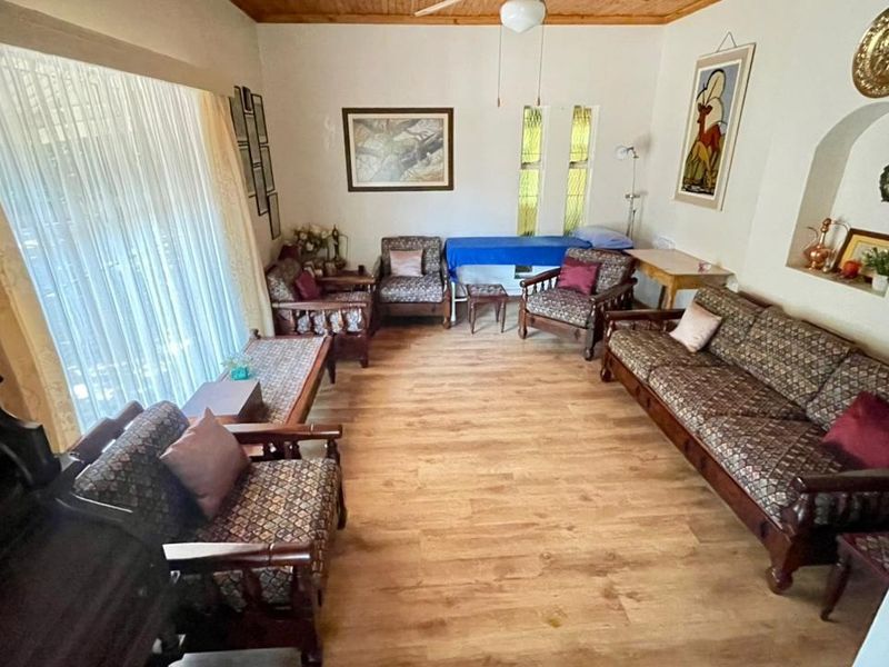A spacious living room featuring laminate flooring, a timber ceiling, and a built-in wall niche, offering a comfortable and functional living space.