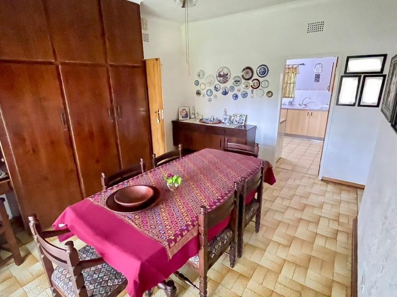Dining room featuring tiled flooring and extensive built-in wooden cabinetry, with a view through to the adjacent kitchen area.