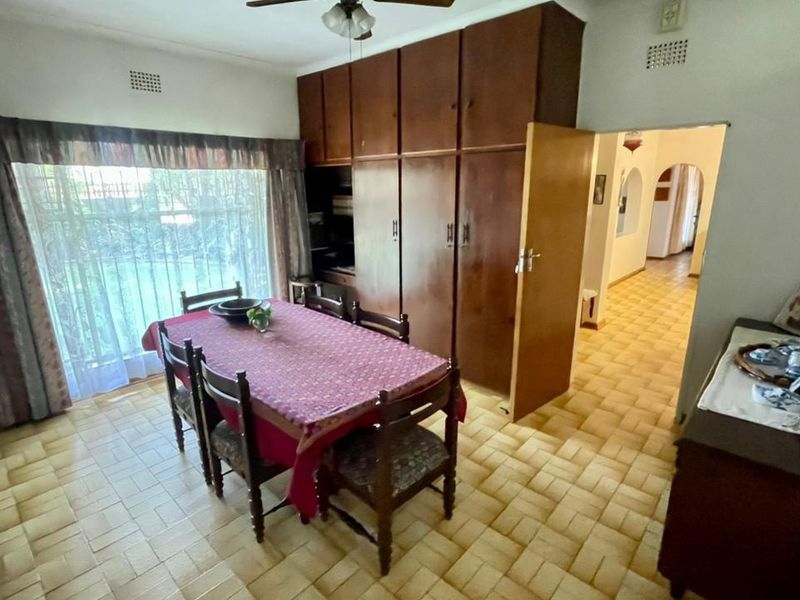 Dining room featuring built-in wooden cupboards, tiled flooring, and a ceiling fan, providing direct access to the hallway.