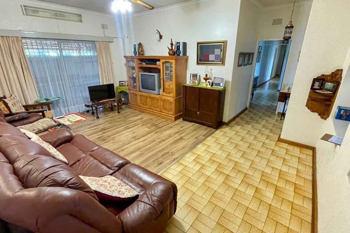 Spacious living room featuring a combination of laminate and ceramic tile flooring, ceiling fan, and access to the exterior via sliding glass doors.