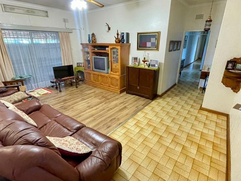 Spacious living room featuring a combination of laminate and ceramic tile flooring, ceiling fan, and access to the exterior via sliding glass doors.