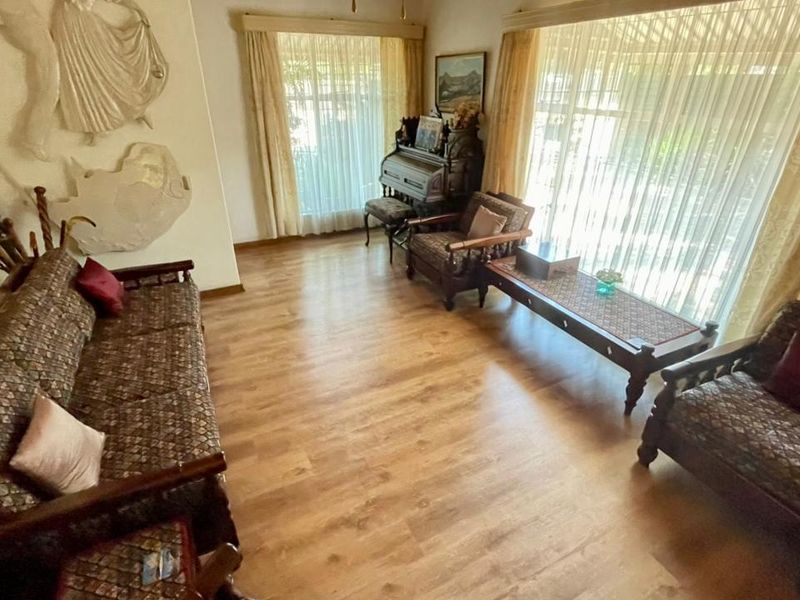 A spacious living room featuring light-toned laminate flooring, large windows allowing ample natural light, and a decorative recessed wall niche.
