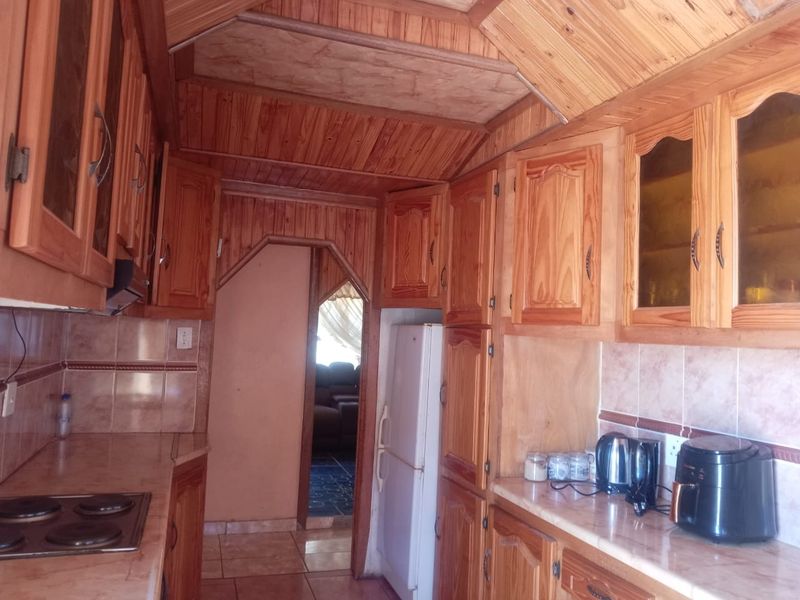 A traditional kitchen featuring extensive wooden cabinetry, tiled backsplash, and tiled flooring, offering a warm, rustic aesthetic with potential for modern updates.
