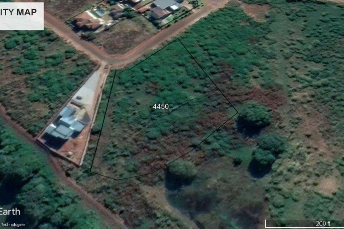 Aerial view of a vacant residential plot of land, showing surrounding neighborhood infrastructure and natural vegetation.