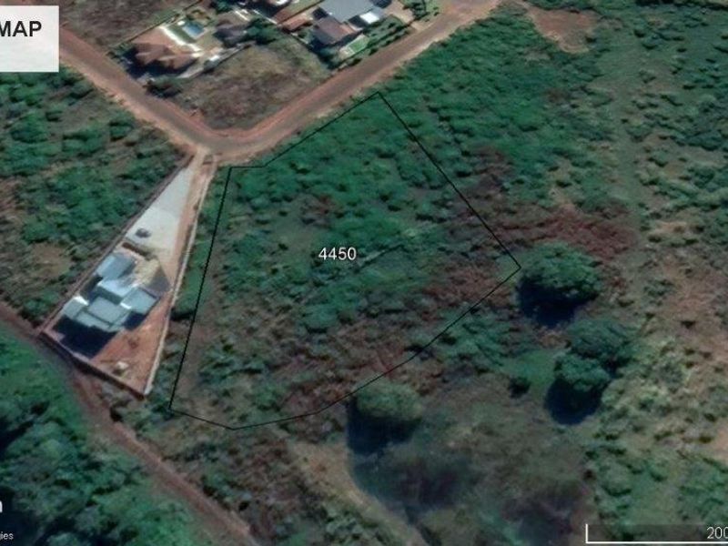 Aerial view of a vacant residential plot of land, showing surrounding neighborhood infrastructure and natural vegetation.