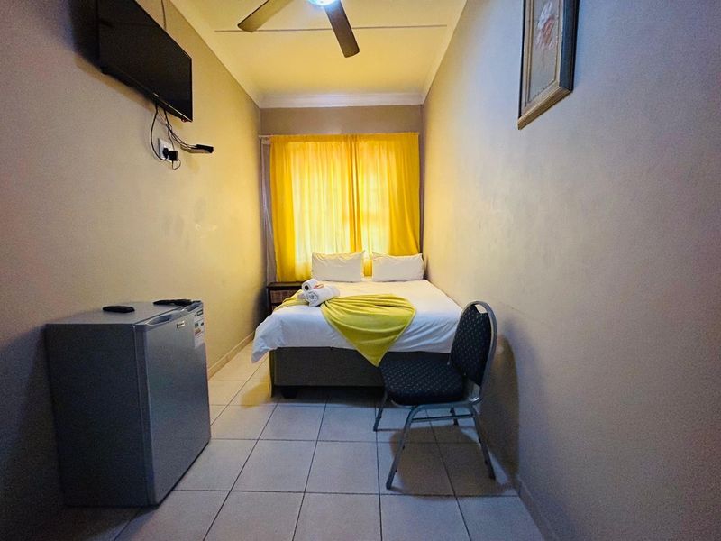 A compact bedroom featuring tiled flooring and a ceiling fan, providing a functional and straightforward sleeping space.