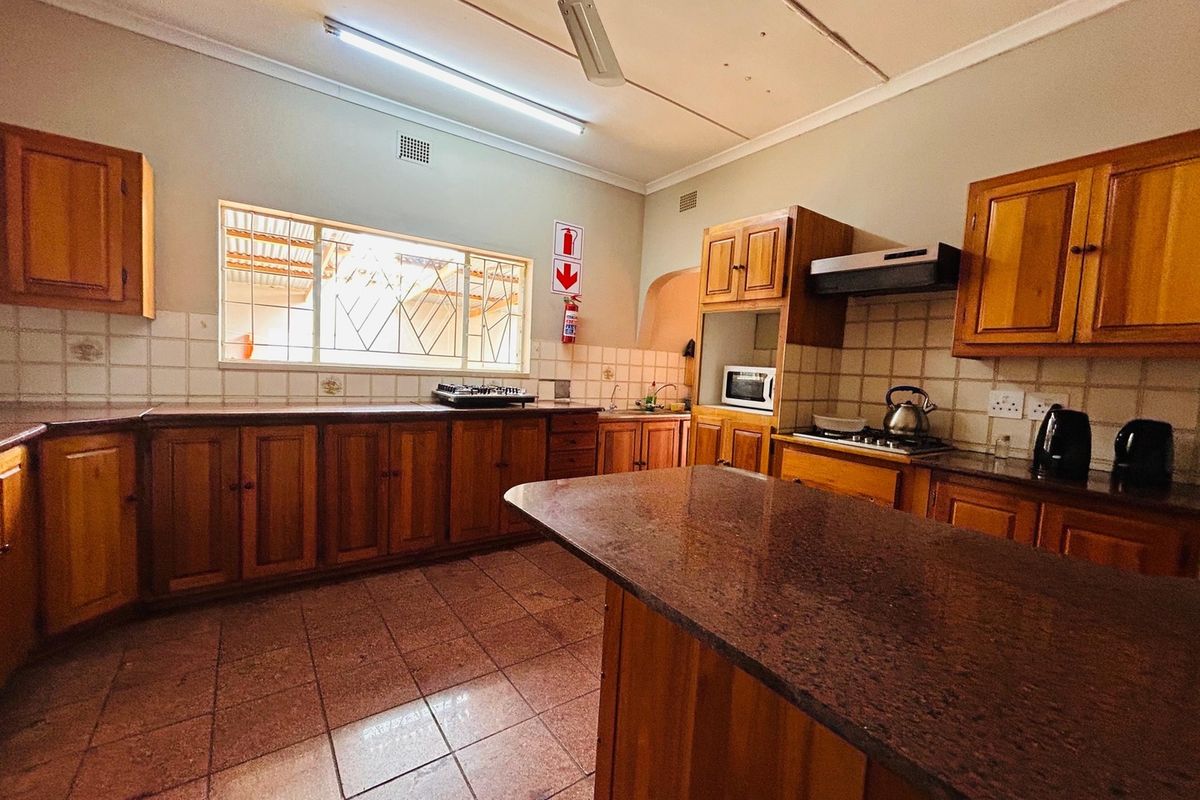 Spacious kitchen featuring wooden cabinetry, granite countertops, tiled backsplash, and built-in appliances, offering a functional layout with ample storage space.