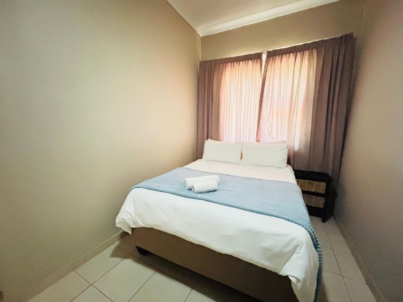 A compact bedroom featuring neutral wall finishes and tiled flooring, providing a functional and comfortable sleeping space.