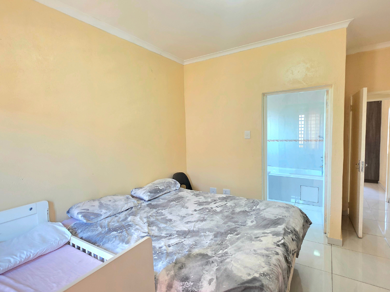A bedroom featuring tiled flooring and direct access to an en-suite bathroom, with neutral wall finishes and standard architectural detailing.
