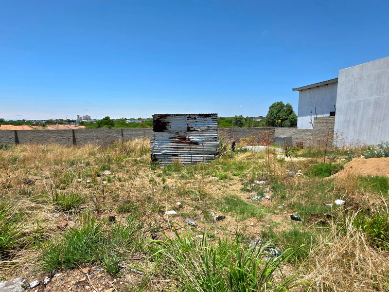 Vacant residential land featuring a perimeter brick wall and a dilapidated corrugated metal shed structure.