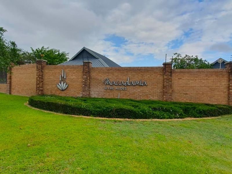 A well-maintained brick boundary wall and landscaped garden at the entrance of Macadamia at The Aloes residential estate.