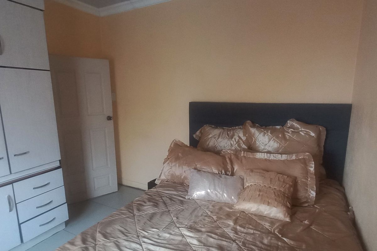 A bedroom featuring built-in cupboards and tiled flooring, providing a functional space with neutral wall tones.