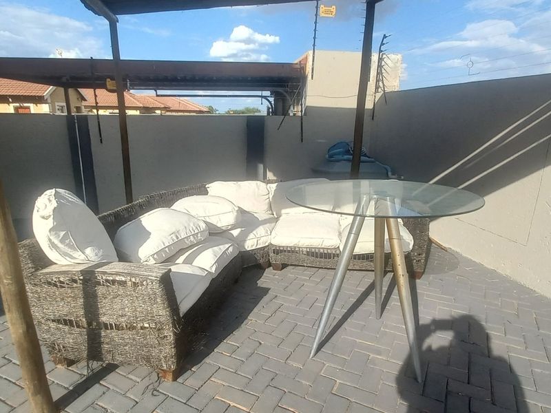 A covered outdoor patio area featuring paved flooring, timber support posts, and perimeter walls with integrated electric fencing.