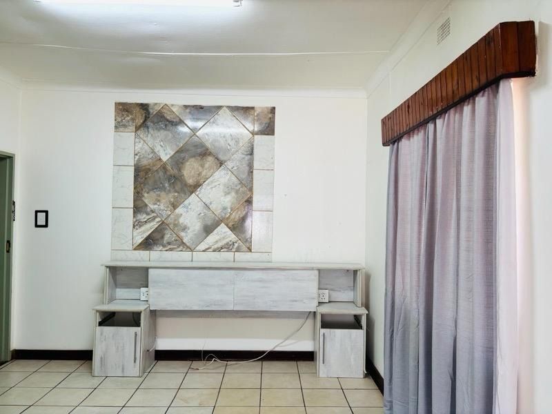 A bedroom featuring ceramic floor tiles, a built-in headboard unit with integrated storage, and decorative wall tiling.