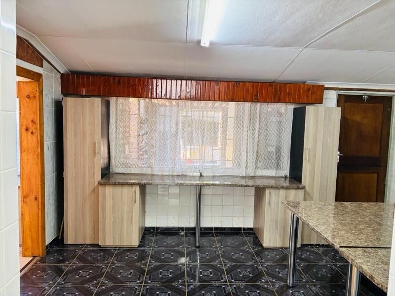 A functional kitchen space featuring laminate cabinetry, granite countertops, and tiled flooring, offering a clean and practical layout ready for updates.