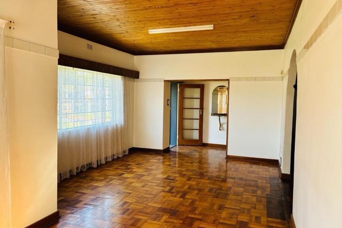 Spacious living area featuring classic parquet flooring and a timber tongue and groove ceiling, offering a neutral canvas for renovation.