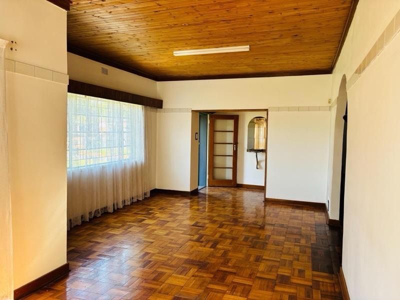 Spacious living area featuring classic parquet flooring and a timber tongue and groove ceiling, offering a neutral canvas for renovation.