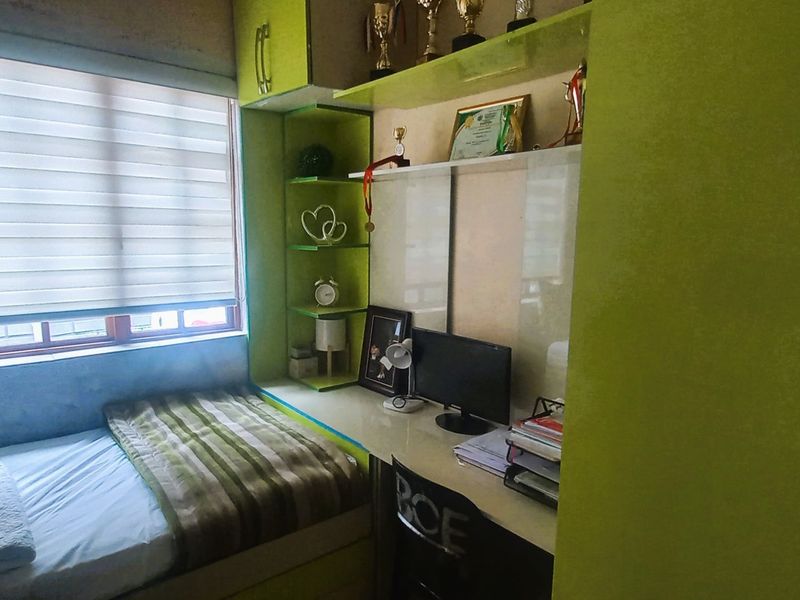 A compact bedroom featuring custom built-in cabinetry, including a desk, shelving, and wardrobe, with integrated window blinds.