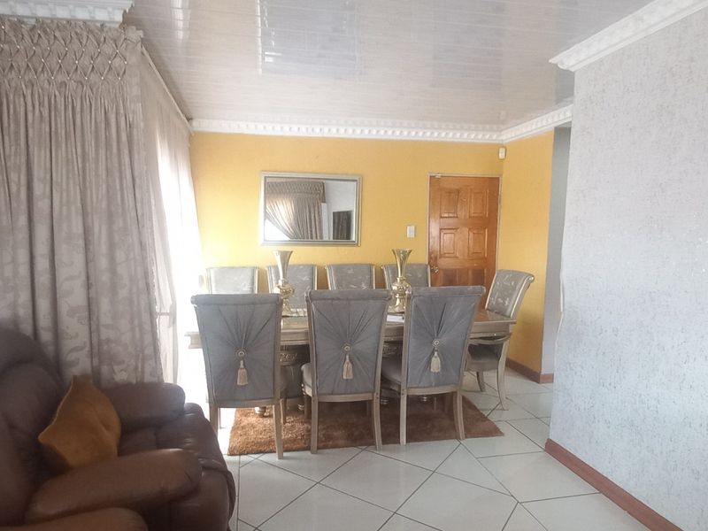 A dining area featuring tiled flooring, decorative ceiling cornicing, and a glossy ceiling finish, providing a functional space for family meals.