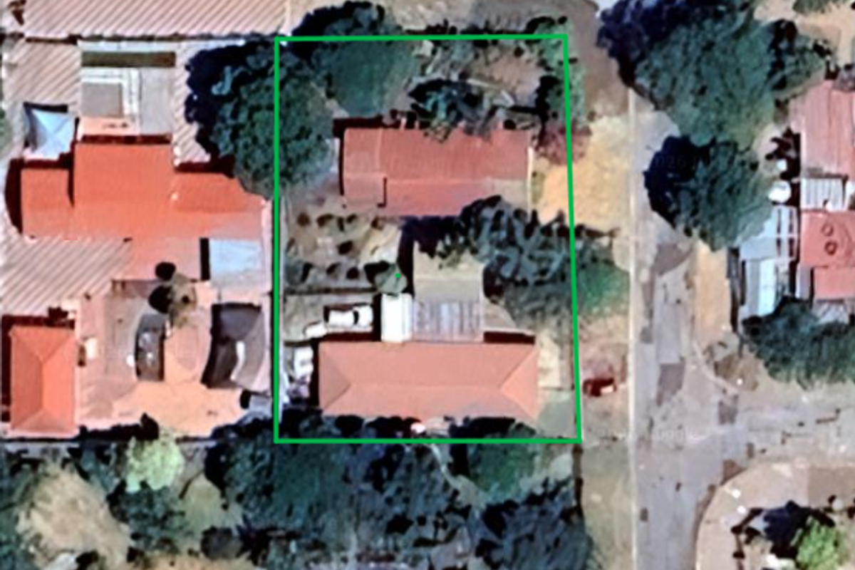 Aerial view of the property showing the building footprint, roof structure, and surrounding garden area.