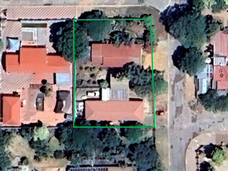 Aerial view of the property showing the building footprint, roof structure, and surrounding garden area.