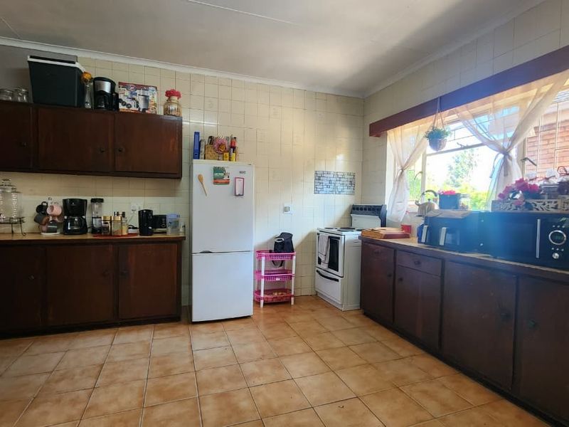 A functional kitchen featuring dark wood cabinetry, tiled walls and flooring, and a large window providing natural light.